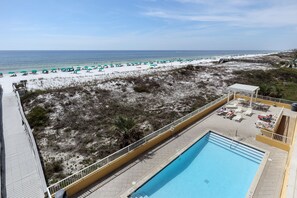 Área da piscina com vista para a praia e o oceano.