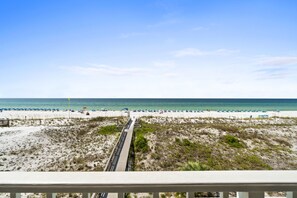 A beach with a wooden boardwalk leading to the water, sandy dunes, and beach umbrellas.