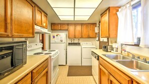 Una cocina funcional con armarios de madera, microondas, estufa, refrigerador y lavavajillas.