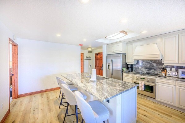 A modern kitchen with a marble island, stainless steel appliances, and white cabinetry.