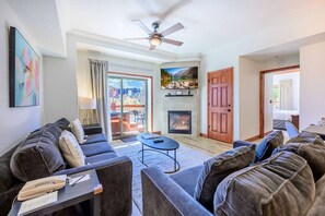 A living room with a sofa set, a coffee table, a fireplace, and a ceiling fan.