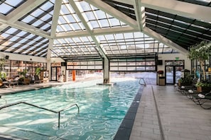 An indoor swimming pool with a glass ceiling, surrounded by lounge chairs and potted plants. - Westgate 4408 (Park City)