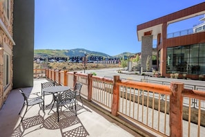 A balcony with outdoor furniture, a view of a road, and a building with large windows. - Westgate 4408 (Park City)