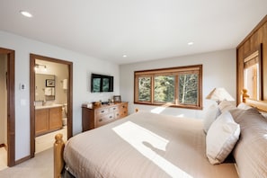 A bedroom with a large bed, a dresser, a television, and a window with a view of trees. - Teewinot D5: Teton Village- Beautiful- Top Floor- Sleeps 10- Pool Access (Teton Village)