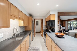 A modern kitchen with wooden cabinets, stainless steel appliances, and a large island with a copper bowl. - Teewinot D5: Teton Village- Beautiful- Top Floor- Sleeps 10- Pool Access (Teton Village)