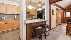 A kitchen with wooden cabinets, a granite countertop, and two bar stools.