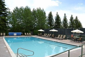 A rectangular swimming pool with a metal ladder, surrounded by lounge chairs and umbrellas. - Teewinot D5: Teton Village- Beautiful- Top Floor- Sleeps 10- Pool Access (Teton Village)