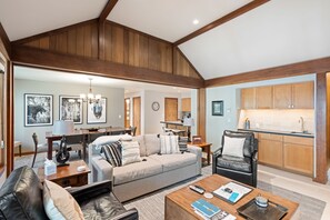 A spacious living room with a sofa, coffee table, and a dining area with a chandelier. - Teewinot D5: Teton Village- Beautiful- Top Floor- Sleeps 10- Pool Access (Teton Village)