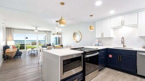 Een moderne keuken met een centraal eiland, roestvrijstalen apparatuur en uitzicht op de buitenruimte.