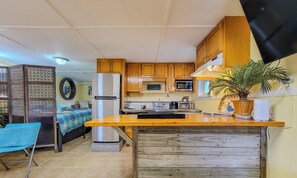 A compact kitchen with wooden cabinets, a refrigerator, a microwave, and a sink.