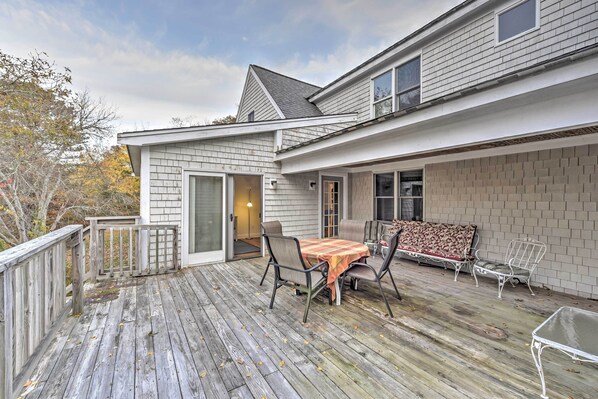 A wooden deck with a table and chairs, a covered patio area, and a brick wall.