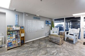 Un espace d’accueil comprenant un panneau d’affichage, un bureau, une chaise et donnant sur le parking.