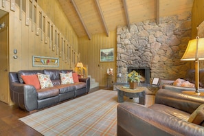 A cozy living room with a stone fireplace, leather sofas, and a wooden ceiling. - Lake Arrowhead Family Home w/ Game Room (Lake Arrowhead)