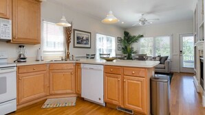 A kitchen with wooden cabinets, a dishwasher, a coffee maker, and a dining area with a sofa. - Charming 3 BR townhouse with sound views! (Wrightsville Beach)