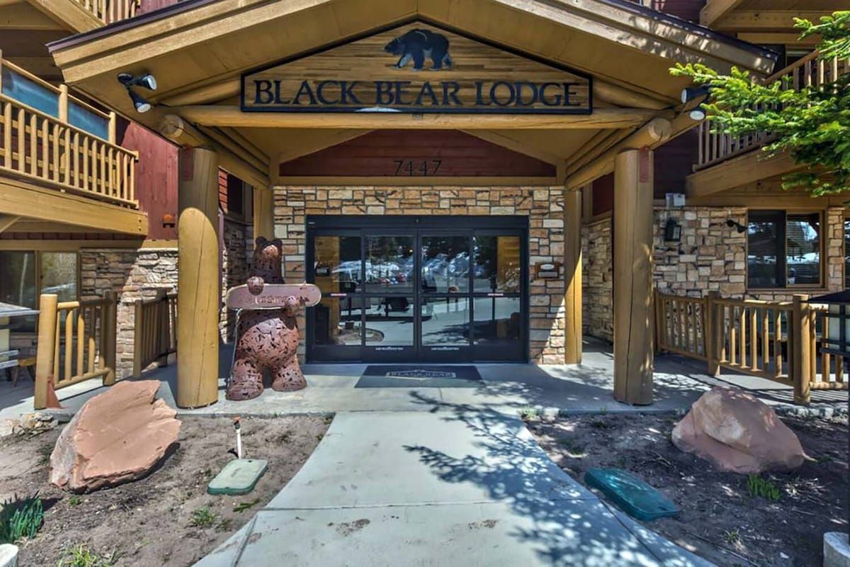 Het uiterlijk van Black Bear Lodge met een stenen gevel, een houten ingang en een beerbeeld.