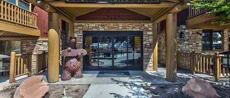 Het uiterlijk van Black Bear Lodge met een stenen gevel, een houten ingang en een beerbeeld.