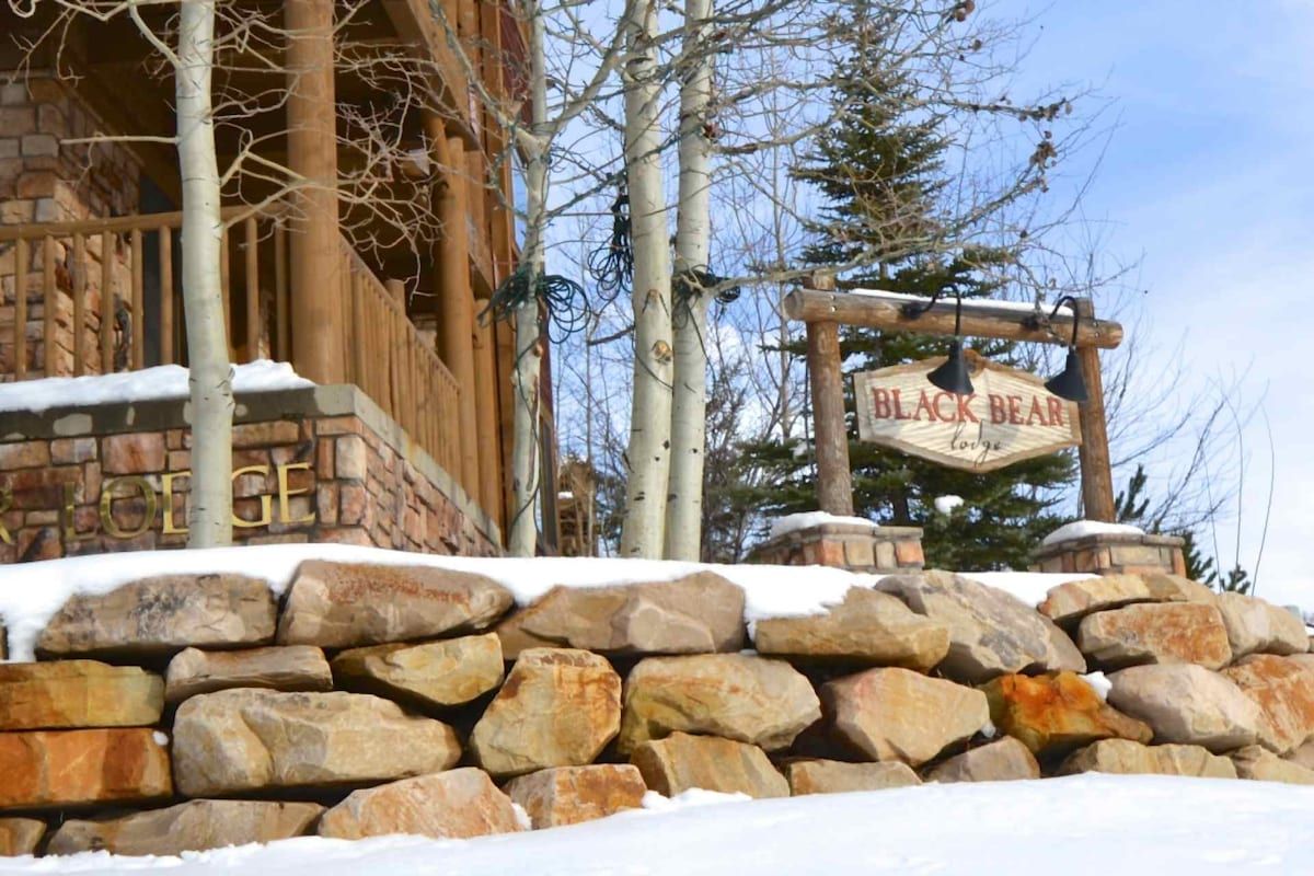 A stone wall with a sign for 'Black Bear Lodge.'