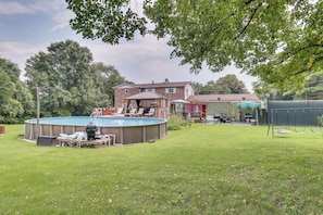 Un jardin avec une piscine, une terrasse couverte et une balançoire.