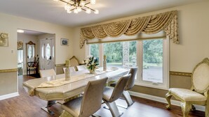 A dining area with a long table, chairs, and a chandelier.