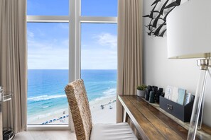Enjoy a serene ocean view from the large window, with a comfortable workspace and a touch of greenery.