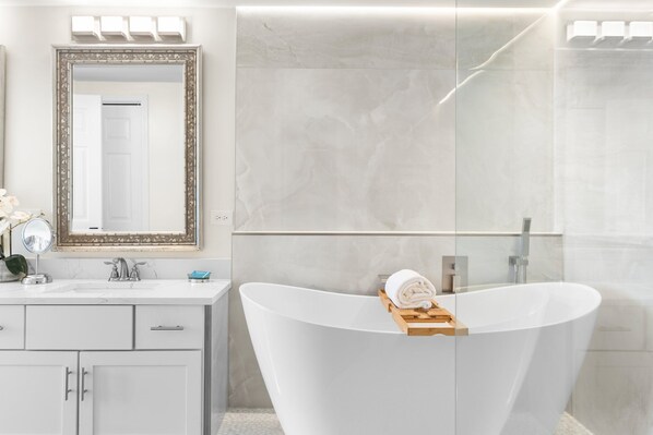 A modern bathroom with a freestanding bathtub, a large mirror, and a vanity with a sink and cabinet. - Beach Front, Floor to Ceiling Windows, Updated Kitchen (Destin)