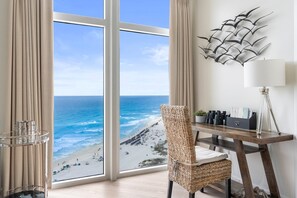 Enjoy ocean views from the large window in this room, featuring a desk, chair, and decorative wall piece.