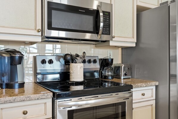 A kitchen with a stainless steel microwave, stove, oven, and a coffee maker.