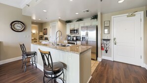 A modern kitchen with a central island, stainless steel appliances, and a dining area with two chairs.