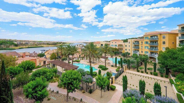 A resort with a swimming pool, palm trees, and a view of a river.