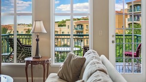 A room with a view of a balcony, a lamp, and a chair.