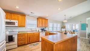A kitchen with wooden cabinets, a central island, a microwave, an oven, and a sink. - Bali Hai - Kitty Hawk MP 3, 50 Yards to Beach, Breathtaking Views, Open Decks (Kitty Hawk)