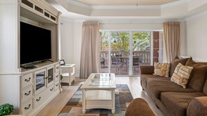 A living room with a flat-screen TV, a ceiling fan, a glass coffee table, a brown sofa, and a sliding glass door leading to an outdoor patio. - 15 Minutes to Disney! | Games Console | Smart TV | Blu-Ray | Free WiFi (Kissimmee)