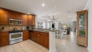 A spacious kitchen with wooden cabinets, stainless steel appliances, and a large island. - 15 Minutes to Disney! | Games Console | Smart TV | Blu-Ray | Free WiFi (Kissimmee)