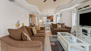 A spacious living room with a large sectional sofa, a glass coffee table, and a ceiling fan. - 15 Minutes to Disney! | Games Console | Smart TV | Blu-Ray | Free WiFi (Kissimmee)