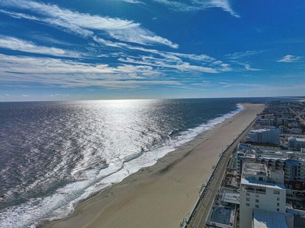 A coastal cityscape with a beach, buildings, and a clear sky.