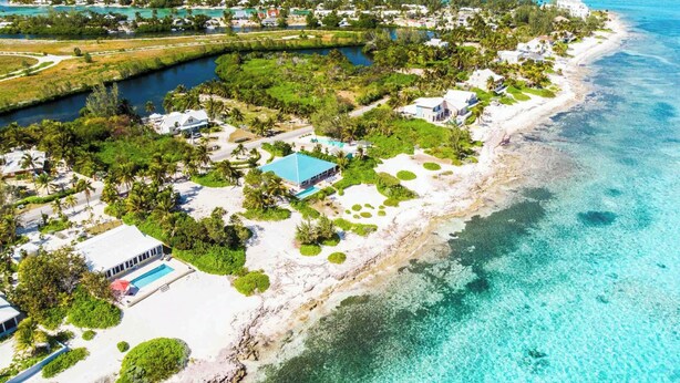 An aerial view of a coastal resort with beachfront properties, a marina, and clear turquoise waters. - Thatch Hill: Beach House w/ Private Pool & Backyard Snorkeling, Walk to the Rum Point Club! (Grand Cayman)