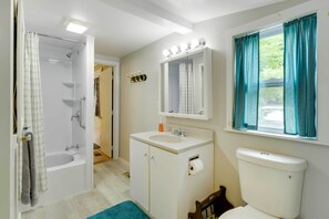 Une salle de bain avec une baignoire, un lavabo, des toilettes et un miroir avec éclairage.