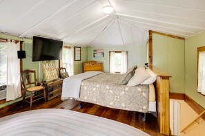 Une chambre confortable avec un lit, une chaise, une commode et un téléviseur fixé au mur.
