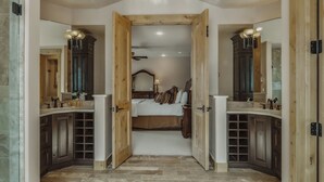 Ein Schlafzimmer mit einem großen Bett, Holzschränken und einem Badezimmer mit Dusche und Waschbecken.