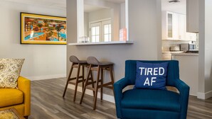 Ein modernes Wohnzimmer mit einem blauen Sessel, einem gelben Sofa und einem Barhocker.