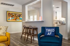 A modern living room with a blue armchair, a yellow sofa, and a bar stool.