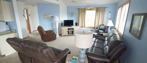 A living room with a sofa set, a TV, and a ceiling fan.