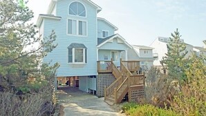 A two-story beach house with a wooden deck and a staircase leading to the entrance. - OS602- Private Pool, Hot Tub, WIFI, Oceanviews, Just Steps to the Beach! (Corolla)