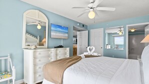 A bedroom with a large bed, a dresser, a mirror, and a ceiling fan.