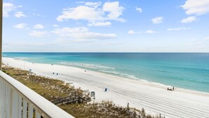 A beach with a clear sky, a sandy shore, and a few people.