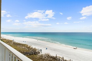 A beach with a clear sky, a sandy shore, and a few people.