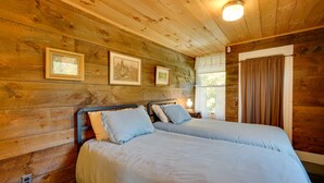 A wooden cabin room with two beds, framed pictures on the wall, and a window with curtains. - 'John's Farmhouse in Mount Snow' on 120 Acres! (Whitingham)