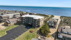 Ein Küstenhotel mit mehreren Gebäuden, einem Parkplatz und Blick auf den Strand.