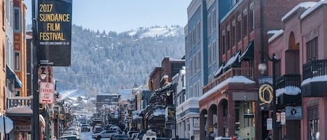 En gata kantad av historiska byggnader, en banderoll för Sundance filmfestival och en tydlig utsikt över snötäckta berg i bakgrunden.