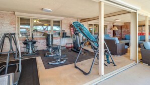 Una palestra con attrezzature per esercizi, un muro in mattoni e un’area salotto con cuscini blu.